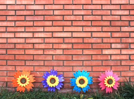 Bright plastic flowers on a brick wall background. Space for text.の写真素材
