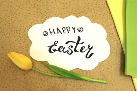 Photo of white paper in the shape of cloud on beige fabric. Happy Easter - hand written lettering....