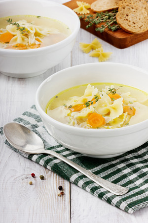 Soup chicken in a white bowl with spoon on a white wooden tableの写真素材