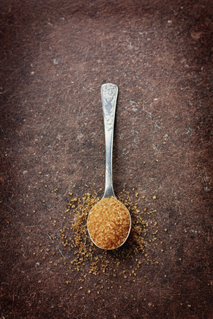 Brown sugar in a spoon on a vintage surfaceの写真素材
