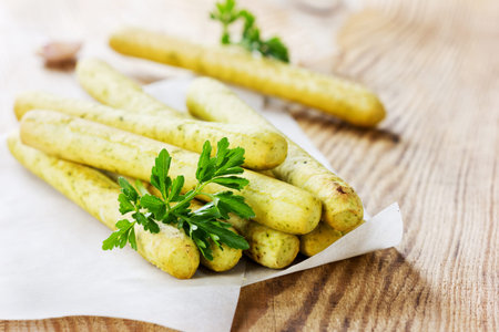Bread sticks with parsley and garlic on a wooden table