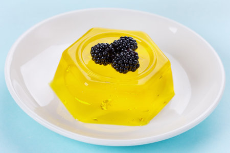 pineapple jelly pudding decorated blackberries on a white plate on a blue background