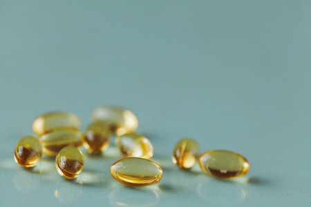 Yellow capsule with vitamin E tocopherol on blue surface, selective focus