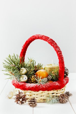 vintage christmas or xmas composition. basket with tangerines, pine cone, golden balls, fir branches and candle.の写真素材