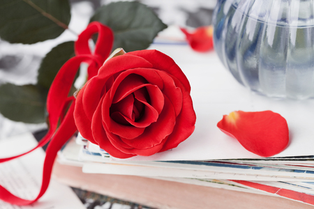 Red rose flower with a stack of postcard, retro photos and vintage bookの写真素材