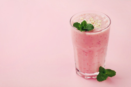 Berry smoothie or milkshake with oats decorated mint leaves on pink background, healthy and delicious breakfastの写真素材