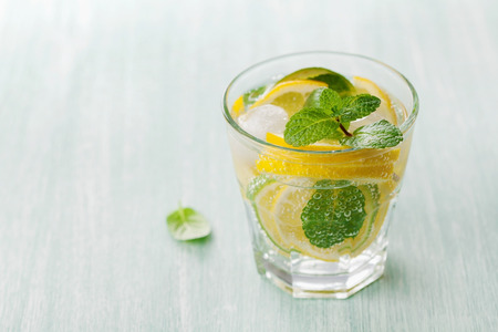 Soda water or mineral water with limes, lemons, ice and mint leaves on light blue background, can be used for detox dietの写真素材