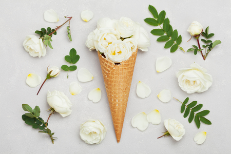 Ice cream of rose flowers in waffle cone on light gray background from above, beautiful floral decoration, vintage color, flat lay stylingの写真素材