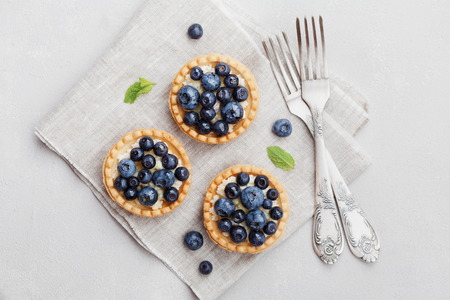 Tartlets with blueberries, bilberry, ricotta and honey syrup on vintage background from above. Delicious dessert. Flat lay styling.の写真素材