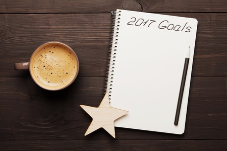 Cup of coffee and notebook with goals for 2017 on wooden table from above. Planning and motivation for the new year concept.の写真素材