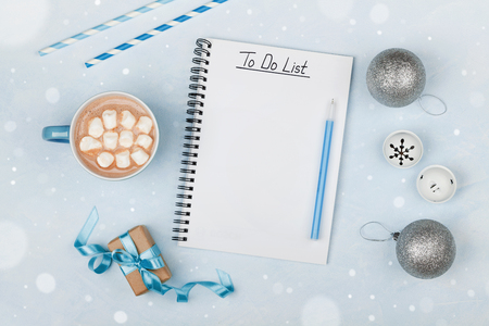 Cup of hot cocoa, gift, holiday decorations and notebook with to do list on blue vintage table from above, christmas planning and mockup. Flat lay style.の写真素材