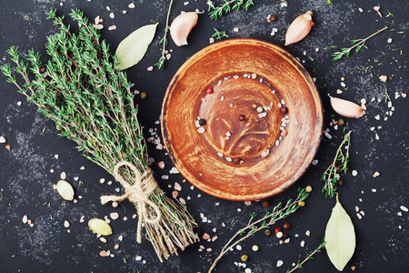 Food background of herb thyme, plate and spices on black kitchen table from above.の写真素材