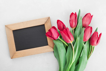 spring tulip flowers and wooden frame with empty space for text on gray stone table top view in flat lay style greeting for birthday womans or mothers dayの写真素材
