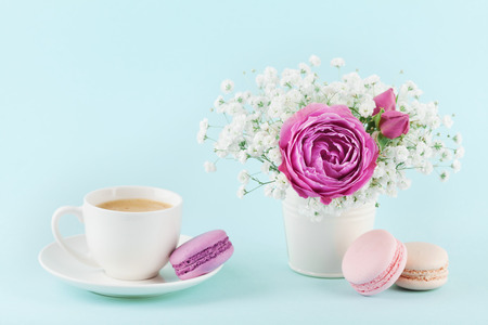 Beautiful pink rose flower and gypsophilla in vase, macaroon and cup of coffee on turquoise vintage table for cozy breakfast.の写真素材