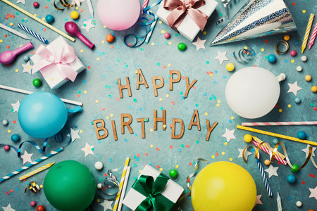 Happy birthday background or greeting card. Colorful festive decoration on turquoise vintage table top view. Flat lay style.の写真素材