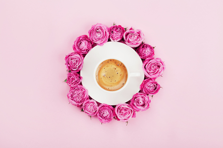 Creative card with coffee cup and beautiful pink rose flowers on pastel background top view in flat lay style.の写真素材