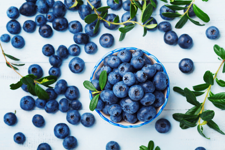 Blueberry or great bilberry in bowl on blue wooden table top view. Organic superfood and healthy nutrition.の写真素材