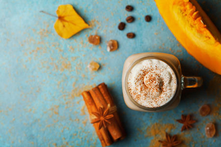 Pumpkin spiced latte or coffee in cup decorated cinnamon on turquoise vintage table top view. Autumn, fall or winter hot drink. Cozy breakfast.の写真素材