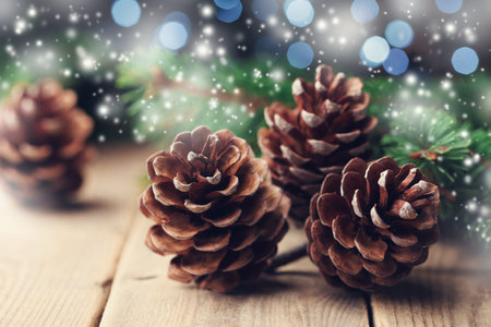 Magic composition with pine cones and fir tree branch on rustic wooden table. Christmas card. Snow...