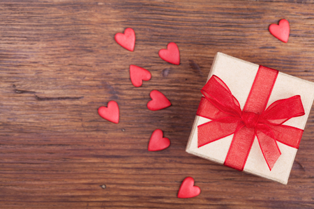 Gift or present box decorated bow ribbon and red hearts on wooden rustic table top view. Valentines or Mother day greeting card. の写真素材