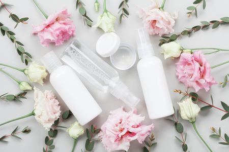 Set of organic natural cosmetic decorated with pastel flowers and green eucalyptus leaves on table top view. Flat lay.の写真素材