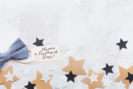 Happy Fathers Day background with greeting tag, bowtie and star confetti on table top view. Flat lay composition.の写真素材