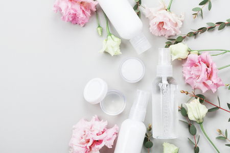 Natural cosmetic set from cream, lotion and moisturizer decorated flowers and green leaves on table top view. Flat lay style.の写真素材