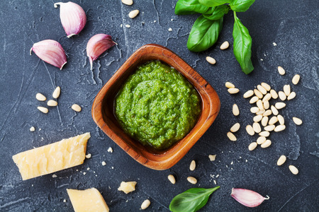 Fresh ingredients and green pesto sauce on black stone table from above.の写真素材
