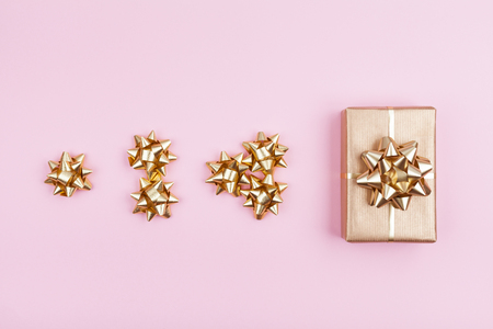 Gift or present box wrapping in golden paper with bows on pink pastel background top view.の写真素材