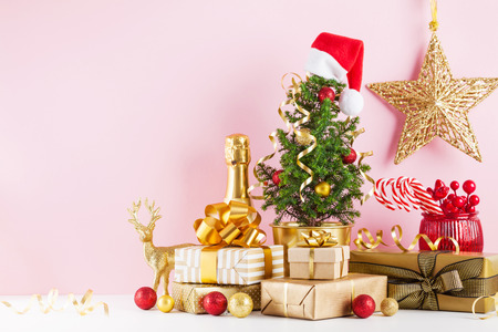 Winter composition with Christmas gift or present boxes, fir tree and golden holiday decorations on pink background.の写真素材