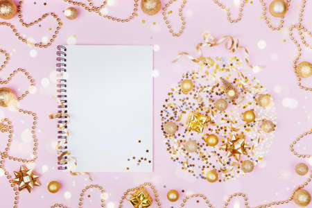 Creative christmas background of holiday ball with decoration and clean notebook for planning on pink pastel table top view. Flat lay style.の写真素材