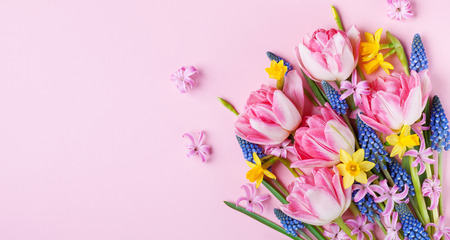 Beautiful spring flowers on pastel pink table top view. Greeting card or banner for International Women Day. Flat lay.の写真素材