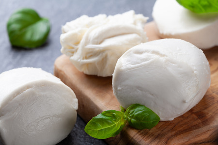 Mozzarella cheese with basil on wooden board. Natural italian dairy product.の写真素材
