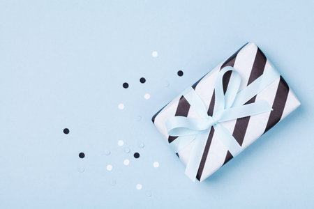 Gift or present box and confetti on blue table top view. Flat lay composition for birthday or Father...