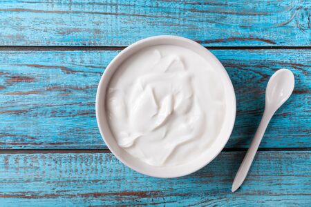 Greek yogurt in bowl on blue wooden table top view.の写真素材