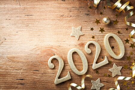 Happy New Year festive background with golden numbers 2020 and Christmas decorations on vintage wooden table top view.の写真素材