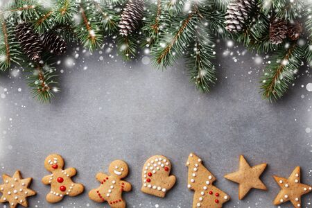 Christmas gingerbread cookies and fir tree with cones top view. Homemade sweet pastries for winter holidays. Snow effect background.の写真素材
