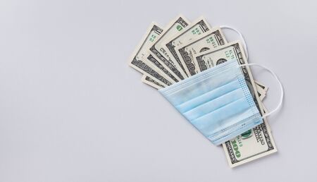 Medical face mask and dollar money, world coronavirus epidemic and economic losses concept. Top viewの写真素材