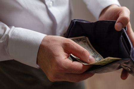 Man holds wallet with the last one dollar. Bankruptcy and unemployment concept.