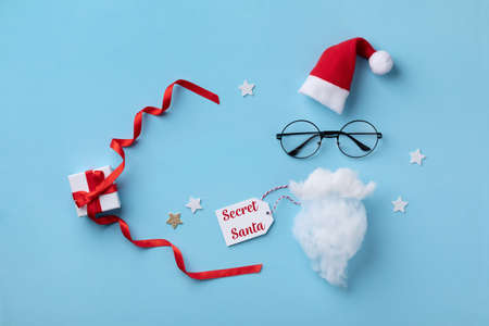 Christmas present or gift for Secret Santa with Santa hat, glasses and beard on blue background.の写真素材