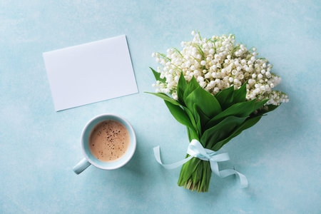 Morning breakfast from fresh coffee cup and spring bouquet of flowers lily of the valley with empty...