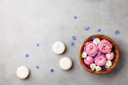 Beauty, aromatherapy and spa background with perfumed water with flowers in wooden bowl and candles...
