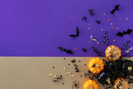 Halloween holiday card with party decorations of pumpkins, bats, spiders on gold violet background top view. Happy halloween greeting poster in flat lay style.の写真素材