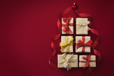 Christmas tree made of gifts and holiday decorations on red background top view. New Year greeting card.の写真素材