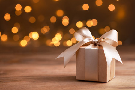 Christmas or birthday gift box against golden bokeh background. Holiday greeting card.