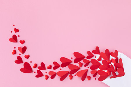 Creative composition on Saint Valentine day. Envelope and various red hearts for love romantic message on pink background. Flat lay.の写真素材