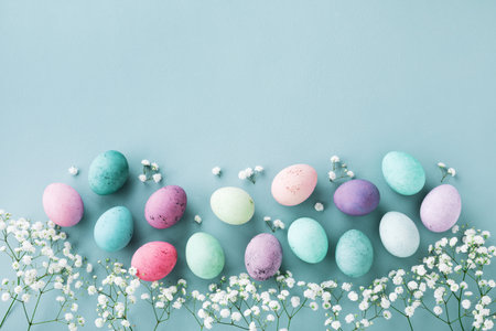 Beautiful Easter border from Easter eggs and gypsophila flowers on pastel blue background top view....