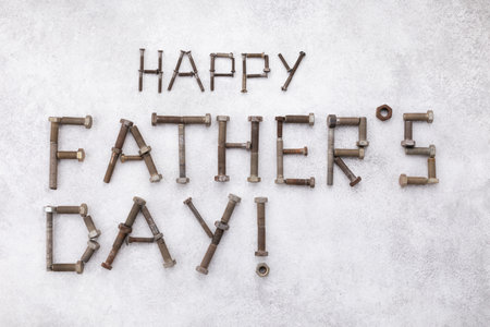 Happy fathers day greeting lettering text from vintage screws top view on white stone background.の写真素材