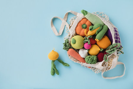 Cute knitting vegetables and fruits for activity, motor and sensory development. Eco friendly toys in cotton bag on blue table.の写真素材