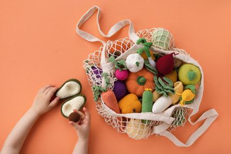 Children hands with cute knitting vegetables and fruits for activity, motor and sensory development. Eco friendly toys in cotton bag concept.の写真素材